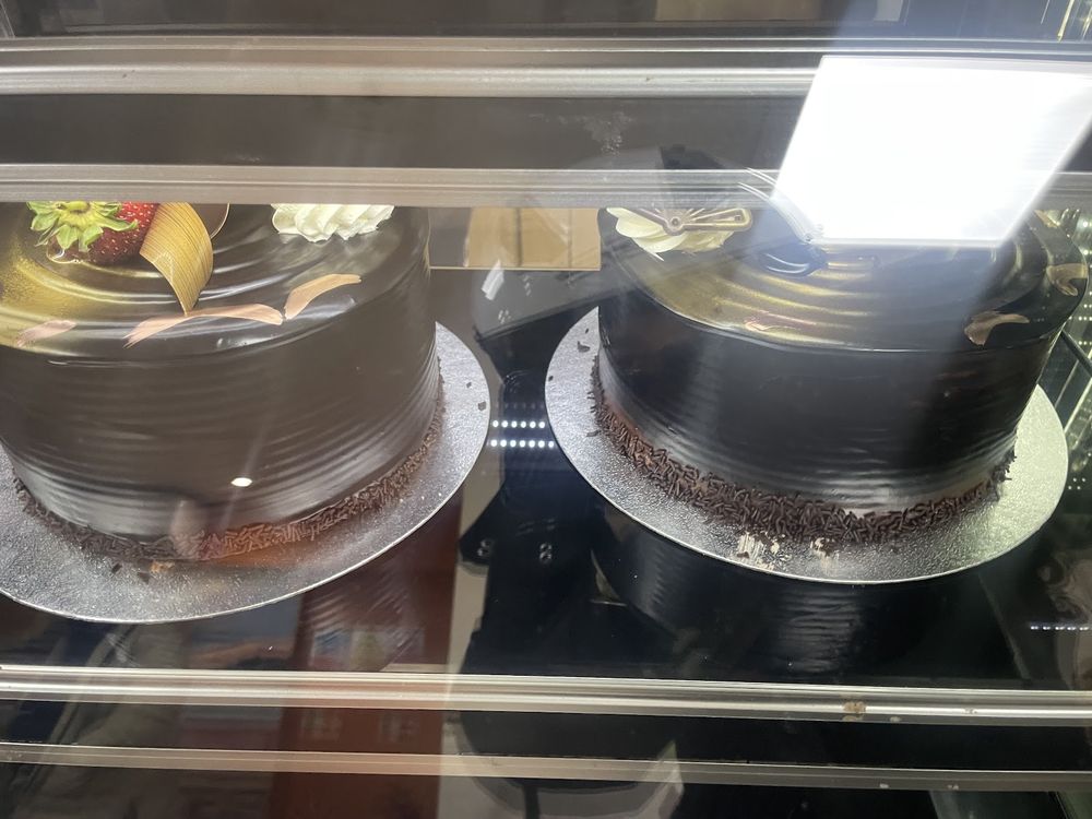 A whole chocolate gateau seen through the display glass